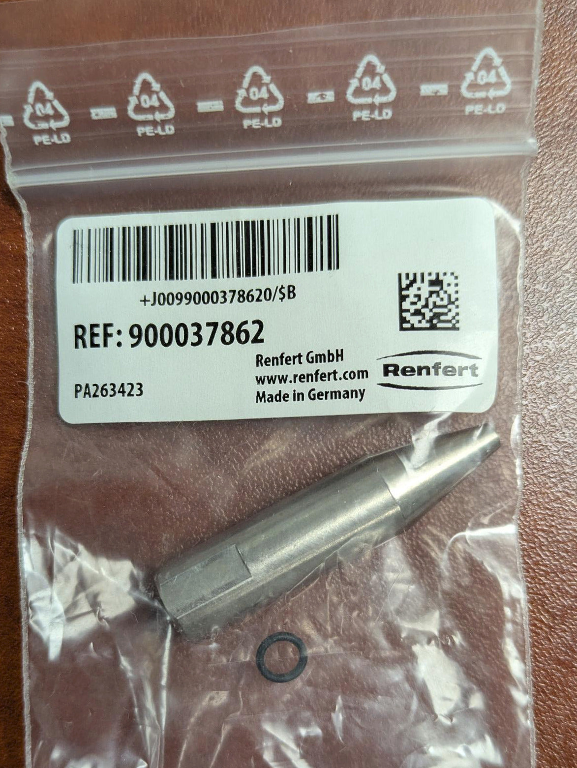 Small metal component in a clear plastic bag with Renfert branding on a wooden surface
